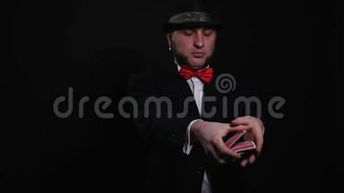 年轻魔术师在黑色背景下表演魔术纸牌魔术表演概念魔术